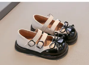 Elegant cream and black girls' Mary Jane shoes with classic bow and buckle details