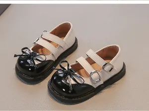 Detail showing children's Mary Jane shoes with black bow and white leather upper