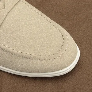 Macro view of beige suede men's loafer toe with meticulous white stitching details.