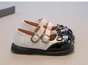 Close-up of sweet girls' Mary Jane shoes with black bow and patent leather toe cap