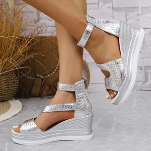 Nahaufnahme der silbernen Keilsandalen mit Krokodilmuster, Fesselriemen und Peeptoe