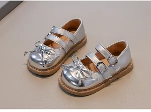 Detailed macro view of shiny silver girls' Mary Jane shoes with bows and double straps