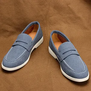 Detailed view of blue suede loafers with white contrast stitching on brown background.