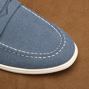 Close-up detail of men's blue suede loafer shoe featuring elegant white contrast stitching