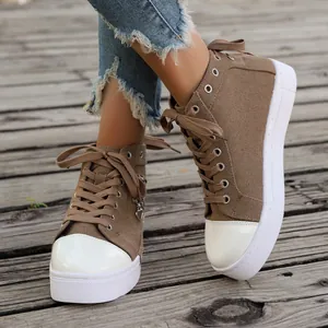 Close-up of brown high-top canvas sneakers with white toe caps on wooden floor