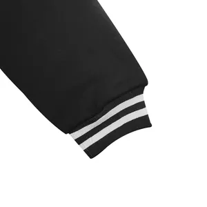 Gros plan du poignet en maille côtelée rayée d'un blouson de baseball noir rétro de qualité