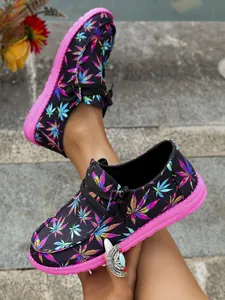 Close-up detail of women's colorful leaf print canvas loafers with vibrant pink soles