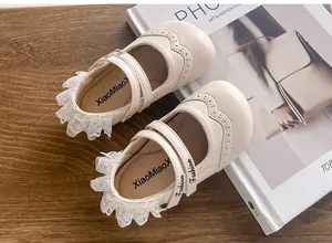 Vue détaillée de chaussures de princesse beiges pour bébés avec bordure en dentelle
