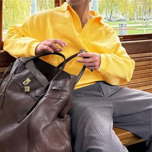 Detalle de una sudadera de manga larga amarilla para hombre con cuello polo clásico.