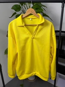 Vista de detalle de una sudadera amarilla para hombre con cuello en V en percha de madera