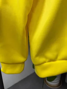 Vista macro detallada de los puños acanalados de la sudadera amarilla brillante y tela