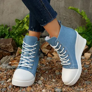 Seitendetail von Damen-Keil-Sneakern aus Denim mit weißen Schnürsenkeln auf Kies