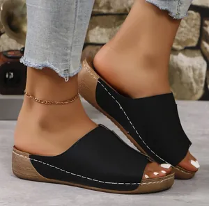 Detalle de sandalias de cuña negras con costuras blancas en contraste