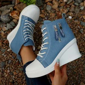 Detailansicht der blauen Denim-Wedge-Sneaker mit dekorativen Reißverschlussbändern