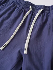 Close-up detail of blue men's cotton linen pants with elastic waist and drawstring.