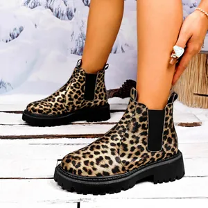 Detailed side view of leopard print Chelsea boots with chunky lug sole on snow.