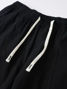 Close-up of elastic waistband and white drawstring on black cotton linen trousers