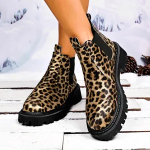 Close-up of stylish leopard print women's Chelsea boots with thick black lug sole in snow.
