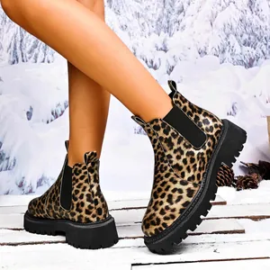 Close-up of leopard print Chelsea boots with thick lug soles in a winter snow setting