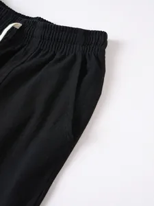 Close-up detail of black cotton-linen casual trousers featuring an elastic waist and pocket.