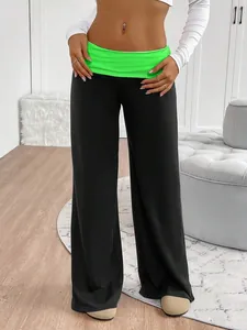 Detailed view of women's black wide-leg yoga pants featuring a neon green waistband.