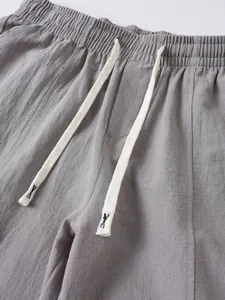 Detailed close-up of drawstring elastic waistband on grey cotton linen trousers