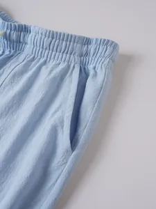 Detail shot of men's light blue cotton linen trousers with elastic waist and side pocket
