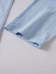 Close-up of light blue cotton linen men's trousers showing hem detail and fabric texture.