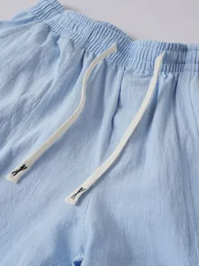 Detail view of men's light blue cotton linen trousers showing elastic waist and drawstring