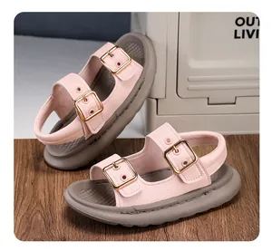 Close-up of children's pink open-toe sandals with dual golden buckle straps.