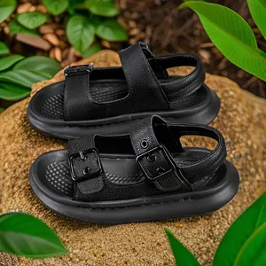 Black children's open-toe beach sandals with double adjustable straps on natural rocks