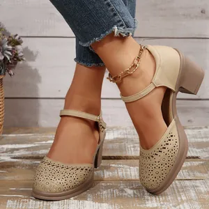Detailed view of women's beige chunky heel pumps with laser-cut floral patterns