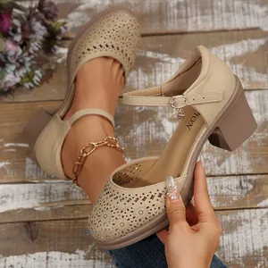 Close-up of beige chunky heel pumps featuring elegant floral laser-cut patterns and strap detail.