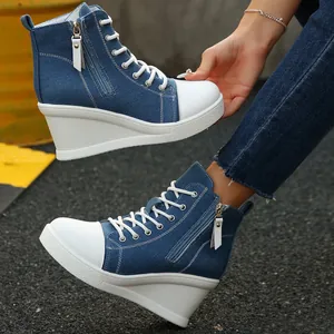 Close-up detail of blue denim high-top wedge sneakers with white soles and side zippers.