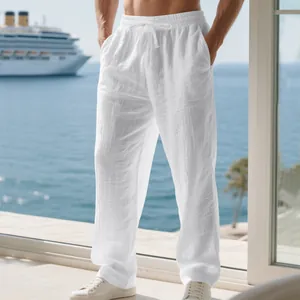 Men's loose white linen trousers with a drawstring waist shown in a resort setting