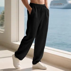 Detailed view of men's loose black linen trousers with a drawstring waist on a balcony
