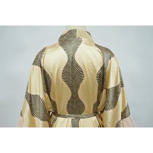 Vue détaillée du dos d'un cache-maillot de plage avec des motifs de feuilles vert et noir.