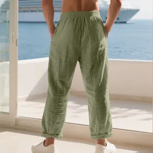 Rear view of stylish men's loose olive green linen trousers worn on a seaside balcony