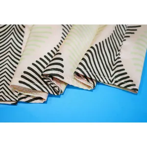 Gros plan sur les coutures de précision et le motif feuille du tissu de plage léger.