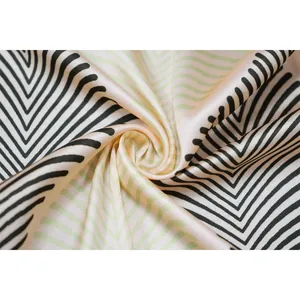 Gros plan sur un tissu satiné doux avec motif géométrique chevron noir et vert