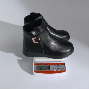 Schwarze flache Winterstiefeletten mit Plüschfutter und Metallschnalle auf einer Waage