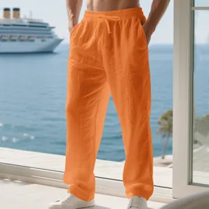 Close-up of men's loose orange linen pants featuring a drawstring elastic waist