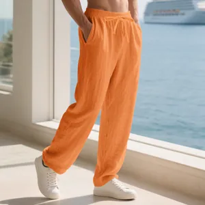 Men's loose orange linen pants with drawstring waist shown on model at a sea resort.