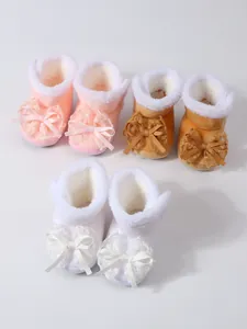 Warme Winter-Babyschuhe mit weichem Plüschfutter und dekorativen Spitzenschleifen in Rosa.