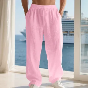 Men's loose pink linen leisure pants with drawstring waist shown in a vacation setting