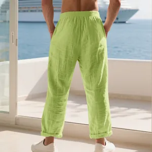 Detailed back view of loose lime green linen trousers for men on a sunny seaside balcony