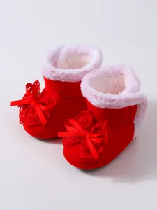 Nahaufnahme von roten Plüsch-Babyschuhen mit niedlichen Spitzenbogendekorationen