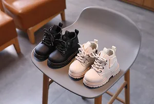 Stylish children's Martin boots in black and beige displayed on a modern chair
