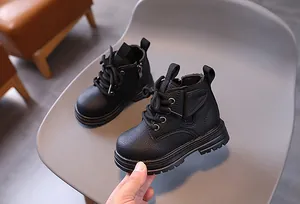 Close-up view of black textured leather children's Martin boots with side zipper and laces