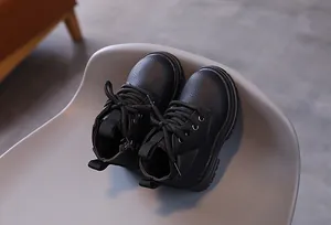 Detailed view of black children's Martin boots with side zipper on a chair